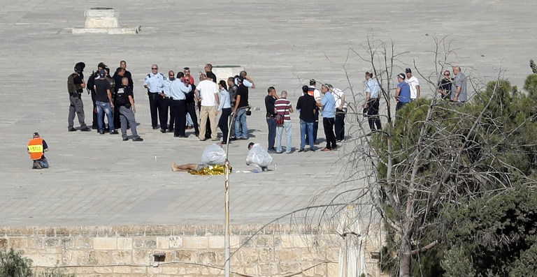 La policía israelí revisa la escena y rodea a un cuerpo (primer plano) donde tres musulmanes dispararon y asesinaron a dos policías israelíes en el Monte del Templo el 14 de julio de 2017. (AFP PHOTO / THOMAS COEX)