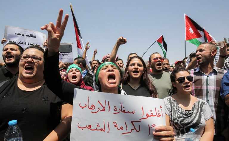 Los manifestantes jordanos agitan las banderas nacionales y cantan consignas durante una manifestación cerca de la embajada israelí en Amman el 28 de julio de 2017, pidiendo el cierre de la embajada, la expulsión del embajador y la cancelación del tratado de paz de 1994 con Israel. (AFP PHOTO / KHALIL MAZRAAWI)