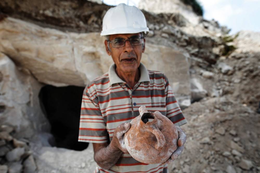 Nashed Abel Halim, excavador arqueológico árabe-israelí, sostiene un antiguo frasco de cerámica descubierto en un sitio de excavación que data del período romano en el pueblo de Reina, cerca de Nazaret, el 10 de agosto de 2017. MENAHEM KAHANA / AFP