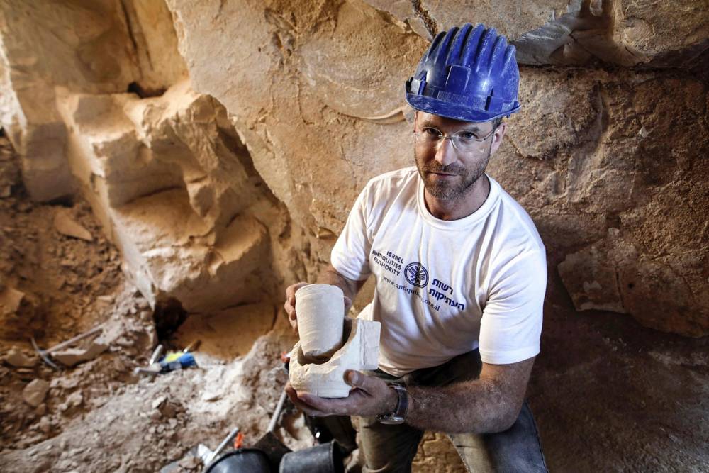 El Dr. Yonatan Adler, director de excavaciones en un sitio que data del período romano, muestra tazones de piedra calcárea y núcleos descubiertos dos meses antes, en el pueblo de Reina, cerca de Nazaret, 10 de agosto de 2017. MENAHEM KAHANA / AFP