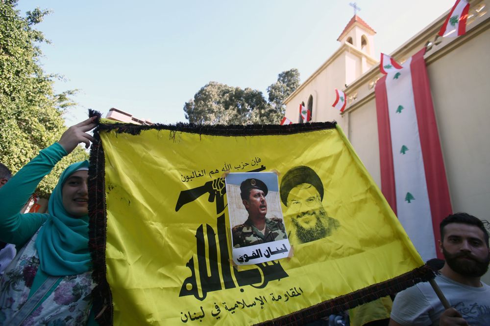 La gente porta una bandera de Hezbolá con una foto del recién nombrado presidente libanés Michel Aoun pegado en ella, en el área de Haret Hreik, los suburbios meridionales de Beirut, Líbano el 31 de octubre de 2016. (Reuters)