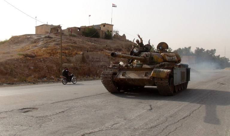 Un combatiente en favor del régimen muestra el signo de la victoria el 21 de agosto de 2016 mientras conduce un tanque en el distrito meridional de Ghweiran en la ciudad de Hasakeh, en el noreste sirio, donde las fuerzas kurdas avanzaban (AFP / STR)