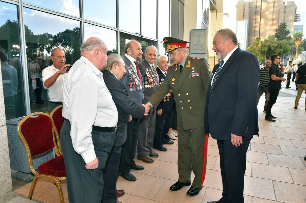 Avigdor Liberman, a la derecha, y el ministro de Defensa ruso, Sergey Shoigu, estrechando la mano de los veteranos en la sede central de Kiria, en Tel Aviv, el 16 de octubre de 2017. (Ariel Hermoni / Ministerio de Defensa)