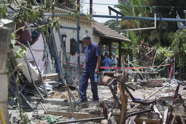 Un hombre inspecciona el daño a una casa después de un ataque con cohetes por terroristas de la Franja de Gaza en la ciudad israelí de Yehud, al lado del Aeropuerto Internacional Ben Gurion de Israel, el 22 de julio de 2014. (Yonatan Sindel / Flash 90)