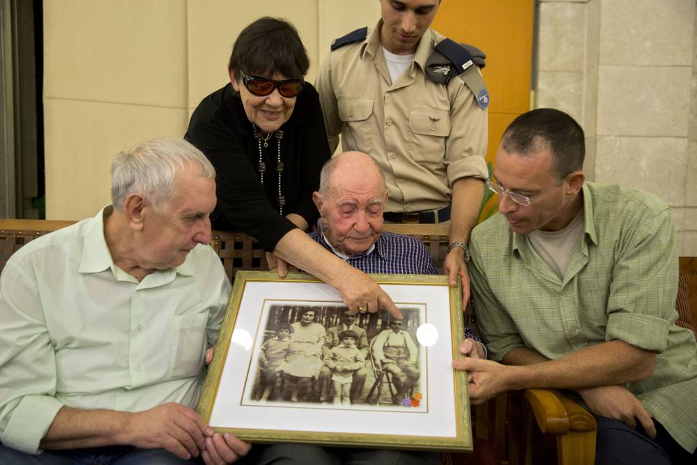 El sobreviviente del Holocausto Eliahu Pietruszka, en el centro, mira una fotografía con Alexandre Pietruszka y su familia en Kfar Saba, 16 de noviembre de 2017. (AP / Sebastian Scheiner)