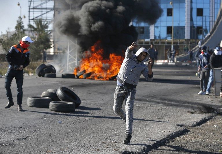 Árabes lanzan piedras hacia las tropas israelíes en un puesto de control israelí cerca de la ciudad de Ramallah el 8 de diciembre de 2017. (AFP / Abbas Momani)