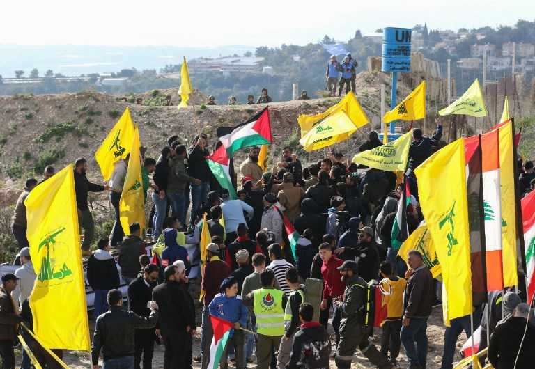 Soldados israelíes (arriba L) y fuerzas de paz de la ONU (arriba R) observan a los partidarios libaneses del movimiento chiita de Hezbolá presencian una manifestación contra la decisión del presidente estadounidense de reconocer a Jerusalén como la capital de Israel el 28 de enero de 2018 en la aldea libanesa del sur de Alma al-Shaab, en la frontera con Israel. (AFP / Mahmoud Zayyat)