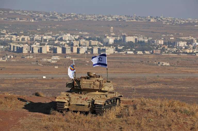 Una bandera Israelí flamea sobre los restos de un tanque en una colina en los Altos del Golán con vistas a la frontera con Siria el 18 de octubre de 2017. (AFP Photo / Jalaa Marey)