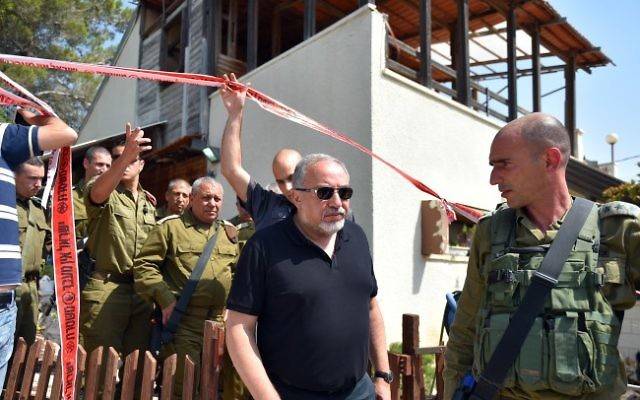 El ministro de defensa Avigdor Liberman (centro) camina ante el jefe del Estado Mayor de las FDI Gadi Eisenkot (cuarta izquierda) mientras visitan el sitio de un ataque terrorista en el poblado judío de Halamish, 22 de julio de 2017 (Ariel Hermoni / Ministerio de Defensa vía Flash 90)