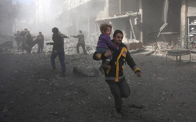 Un hombre sirio porta a un niño herido en un bombardeo del gobierno en la ciudad de Hamouria, en la sitiada región de Ghouta, en las afueras de la capital, Damasco, el 19 de febrero de 2018. (AFP PHOTO / ABDULMONAM EASSA)