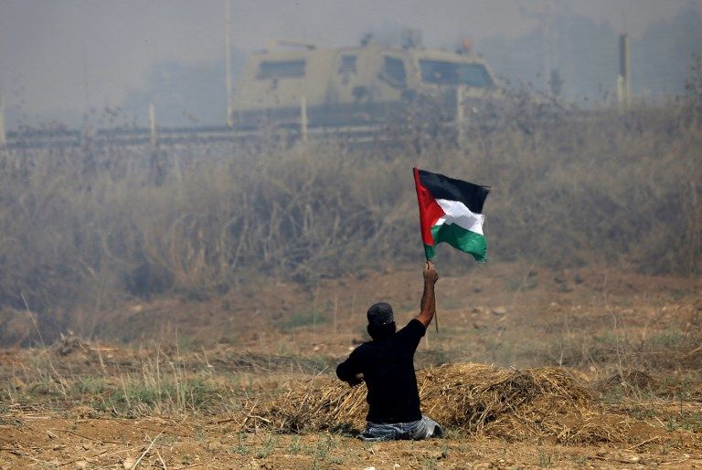 Esta foto tomada el 19 de mayo de 2017 muestra al incitador palestino incapacitado Ibrahim Abu Thurayeh ondeando una bandera palestina durante los enfrentamientos con soldados israelíes luego de una protesta contra el bloqueo en Gaza, cerca de la valla fronteriza al este de la ciudad de Gaza. (MOHAMMED ABED / AFP)