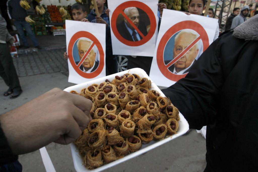 Los palestinos reparten dulces mientras celebran el fallecimiento del ex primer ministro israelí Ariel Sharon en Khan Younis en el sur de la Franja de Gaza, el 11 de enero de 2014. (Crédito de la foto: Abed Rahim Khatib / Flash 90)