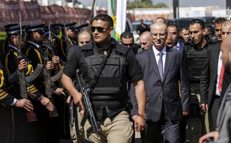 El primer ministro palestino Rami Hamdallah (2do R), escoltado por sus guardaespaldas, es recibido por las fuerzas policiales de Hamás (L) a su llegada a la ciudad de Gaza el 13 de marzo de 2018. (AFP PHOTO / MAHMUD HAMS)