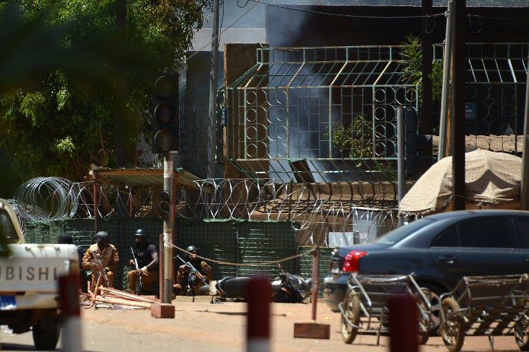 El personal de seguridad se cubre mientras el humo se eleva desde The Institute Francais en Ouagadougou el 2 de marzo de 2018, cuando la capital de Burkina Faso sufría múltiples ataques contra la embajada de Francia, el centro cultural francés y la sede militar del país. (AFP / Ahmed Ouoba)