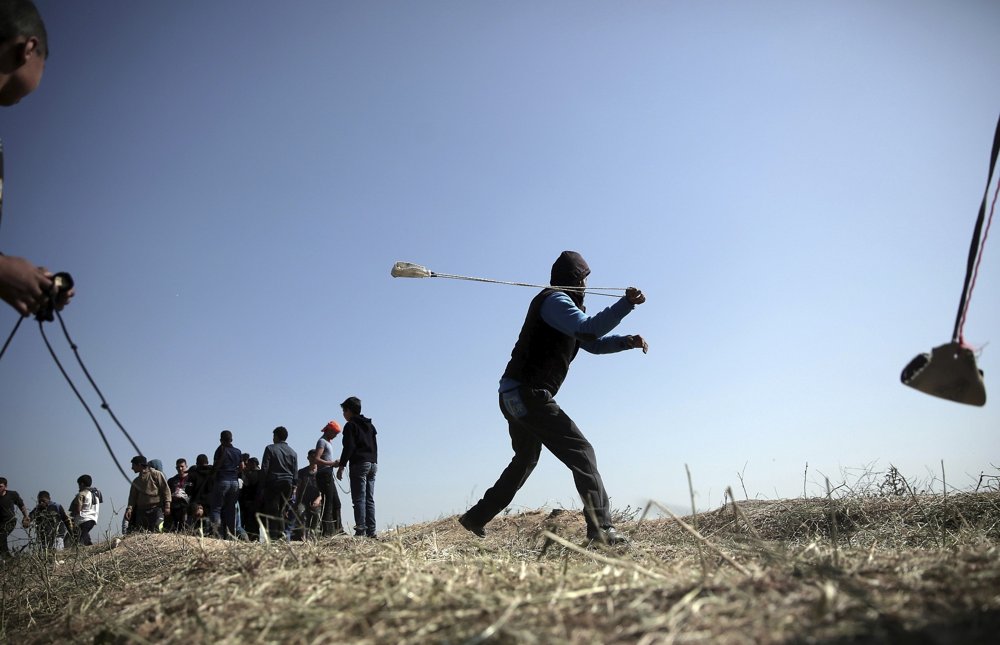 Palestinos lanzan piedras contra soldados israelíes durante una oleada de violencia isamista cerca de la frontera de la Franja de Gaza con Israel, en el este de la ciudad de Gaza, el sábado 31 de marzo de 2018. (AP / Khalil Hamra)