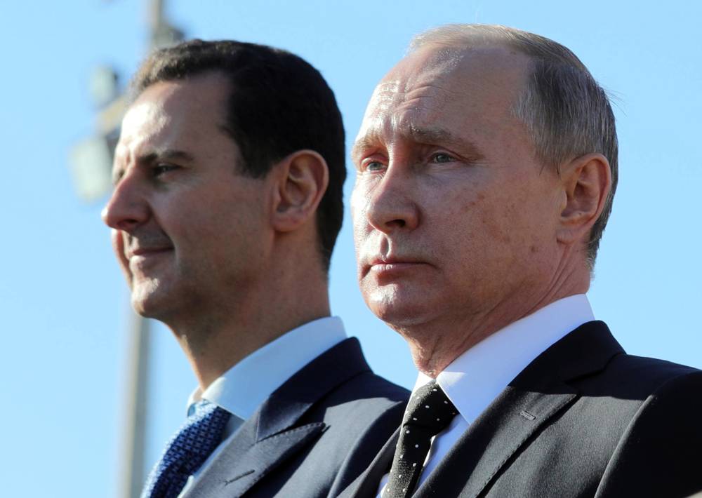 Esta foto del 11 de diciembre de 2017 muestra al presidente ruso, Vladimir Putin, a la derecha, y al presidente sirio, Bashar Assad, observando cómo las tropas marchan en la base aérea de Hemeimeem en Siria. (Mikhail Klimentyev, Sputnik, Kremlin Pool Photo a través de AP, archivo)