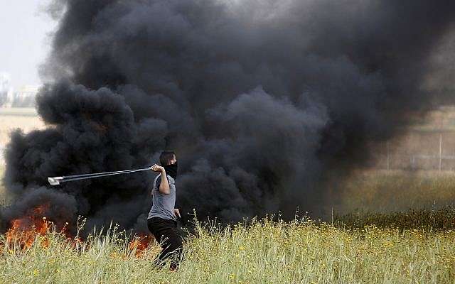 Un atacante palestino arroja rocas letales contra los soldados israelíes durante la ola de ataques islámicos contra las tropas israelíes a lo largo de la frontera de la Franja de Gaza con Israel, al este de Khan Younis, Franja de Gaza, el viernes 30 de marzo de 2018. (AP / Adel Hana)