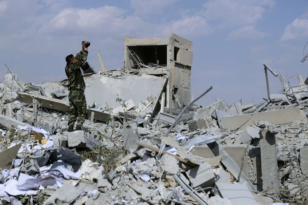 Un soldado sirio filma los daños del Centro de Investigación Científica sirio que fue atacado por ataques militares estadounidenses, británicos y franceses para castigar al presidente Bashar Assad por su ataque químico contra civiles, en Barzeh, cerca de Damasco, Siria, el sábado 14 de abril de 2018 ( AP Photo / Hassan Ammar)