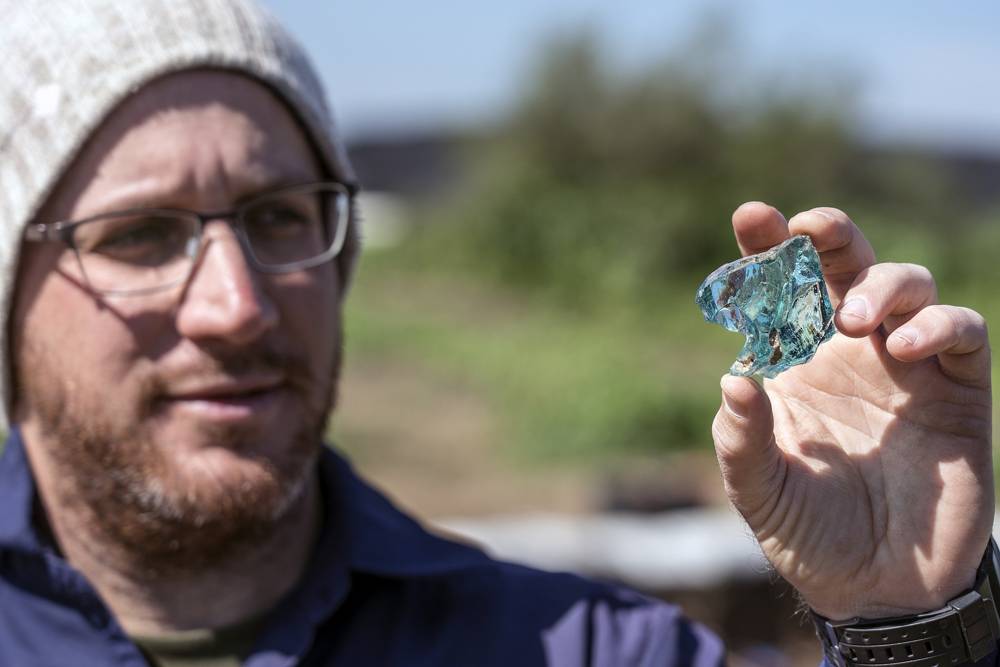 El arqueólogo Yair Amitzur sostiene un trozo de vidrio descubierto durante los preparativos para el nuevo Sendero del Sanedrín en Galilea. Según Amitzur, el hallazgo es evidencia de la industria del vidrio desde el tiempo del Sanedrín. (Yaniv Berman, Autor de Antigüedades de Israel)