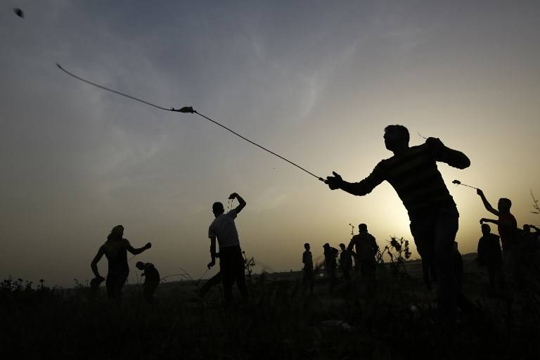 Los atacantes palestinos utilizan hondas para arrojar piedras contra las fuerzas israelíes durante la violencia islamista en la frontera con Israel, al este de la ciudad de Gaza, el 5 de abril de 2018. (AFP PHOTO / MOHAMMED ABED)