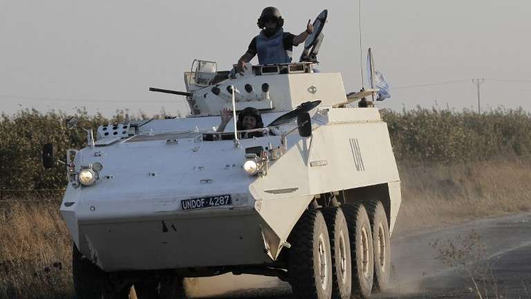 Miembros de la Fuerza de las Naciones Unidas de Observación de la Separación (UNDOF) saludan mientras conducen su vehículo blindado en los Altos del Golán, cerca del cruce de Quneitra, el 30 de agosto de 2014 (AFP / Ahmad Gharabli)