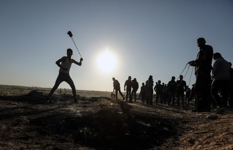 Un atacante palestino arroja piedras hacia los soldados israelíes durante una violenta manifestación a lo largo de la frontera con Israel, al este de la ciudad de Gaza, el 31 de marzo de 2018. (AFP PHOTO / MAHMUD HAMS)