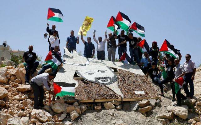 Activistas palestinos se paran alrededor de un retrato en mosaico de 5 × 4 metros (16.5 × 13 pies) de Marwan Barghouti cerca de una instalación militar israelí en la ciudad de Ramallah, martes, 9 de mayo de 2017. (AP Photo / Nasser Shiyoukhi)