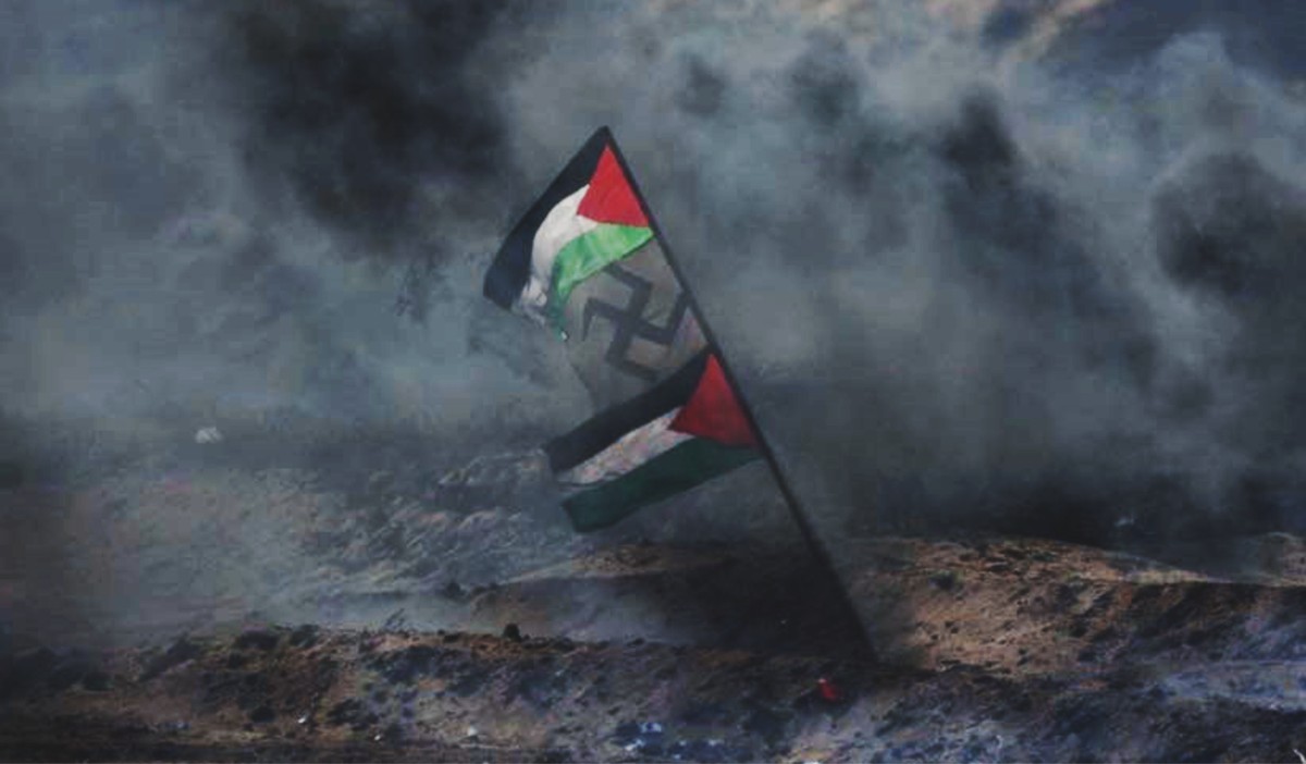 Banderas de la revuelta árabe en versión de la Autoridad Palestina y una cruz svástica se ven en medio del humo negro de las manifestaciones en Gaza, el 6 de abril de 2018 (Unidad de portavoz de las FDI)