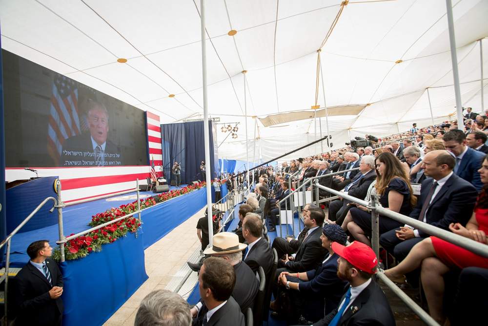 Las personas observan mientras el presidente de EE. UU., Donald Trump, habla en una pantalla de video durante la ceremonia de apertura oficial de la embajada de EE. UU. en Jerusalén el 14 de mayo de 2018. (Yonatan Sindel / Flash 90)