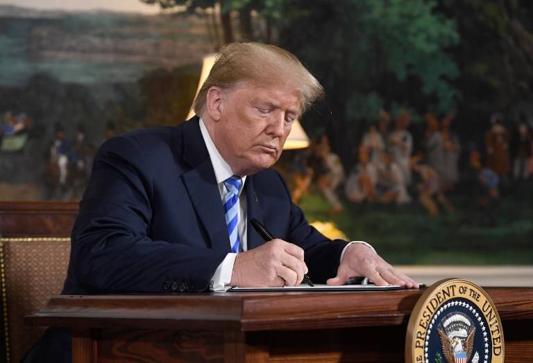 El presidente estadounidense Donald Trump firma un documento que restablece las sanciones contra Irán después de anunciar la retirada de Estados Unidos del acuerdo nuclear de Irán en la sala de recepción diplomática en la Casa Blanca en Washington, DC, el 8 de mayo de 2018. (AFP / Saul Loeb)