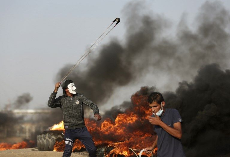 Un islamista palestino utiliza una honda durante los ataques contra las fuerzas israelíes a lo largo de la frontera con la Franja de Gaza, al este de la ciudad de Gaza, el 18 de mayo de 2018. (AFP Photo / Mahmud Hams)