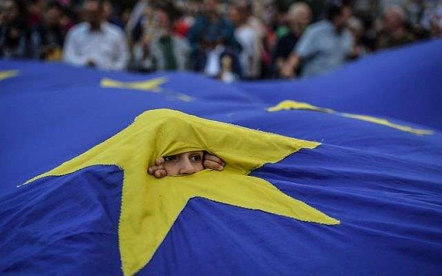 Un joven aparece a través de una bandera europea durante una protesta solicitando la renuncia del primer ministro rumano el 12 de mayo de 2018 frente a la sede del gobierno en Bucarest. (AFP / Daniel MIHAILESCU)