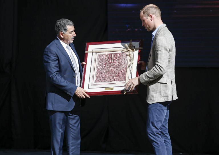 El Príncipe William de Gran Bretaña recibe un regalo de Musa Hadid, el alcalde de Ramallah, en una recepción durante su visita al municipio de la ciudad de Cisjordania el 27 de junio de 2018. (AFP PHOTO / POOL / ABBAS MOMANI)