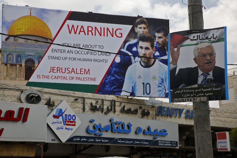 5 de junio de 2018, la imagen muestra un cartel erigido en la ciudad de Hebrón llamando a boicotear a la estrella de fútbol Lionel Messi (l) junto a un retrato del presidente de la Autoridad Palestina Mahmoud Abbas. (AFP PHOTO / HAZEM BADER)