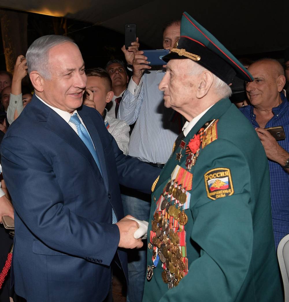 Primer ministro Benjamin Netanyahu con un veterano ruso-israelí en una recepción que marca el Día de Rusia en el Sergei's Courtyard, Jerusalén, 14 de junio de 2018 (Amos Ben-Gershom / GPO)