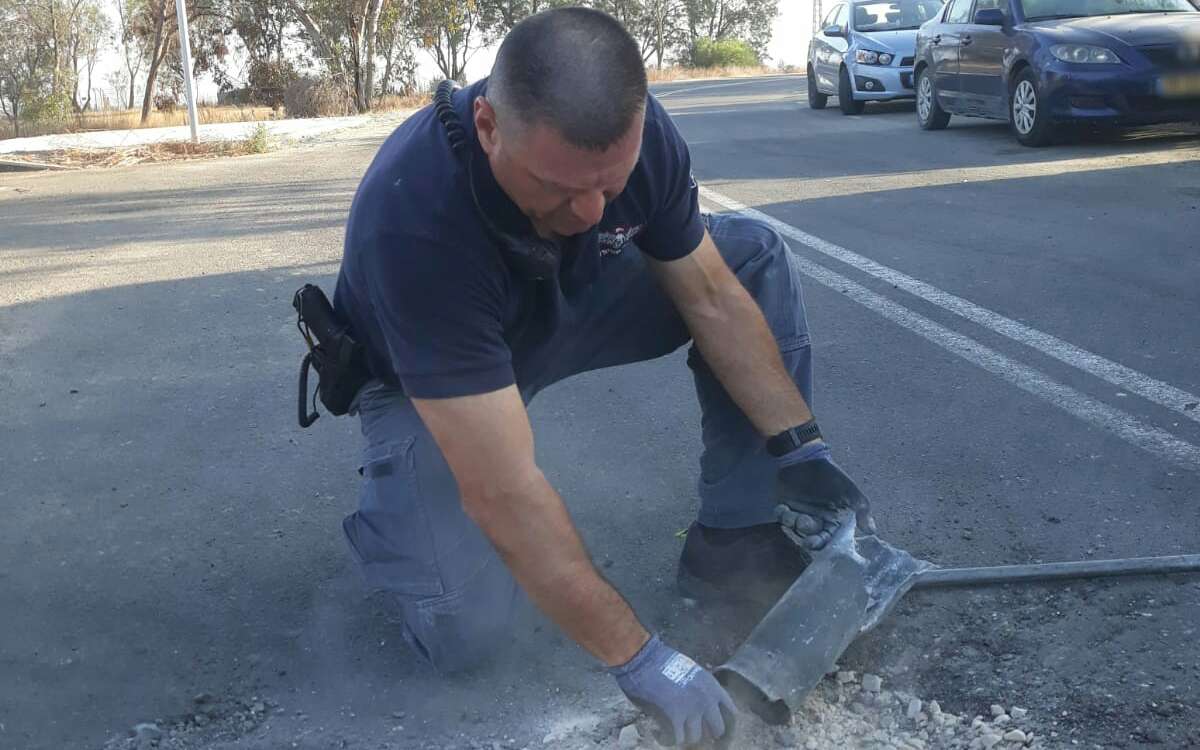 Un zapador de la policía maneja un cohete disparado desde Gaza que aterrizó en una calle en una de las comunidades de la región de Eshkol el 20 de junio de 2018. (Policía de Israel)