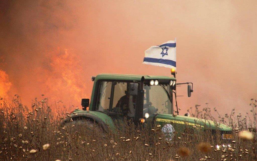 Una foto sin fecha de un agricultor israelí en el área periférica a Gaza que conduce su tractor al lado de un campo incendiado por una cometa encendida que vuela desde la Franja de Gaza. (Cortesía)