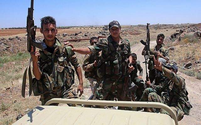 Las fuerzas del gobierno sirio sostienen sus armas en la parte trasera de una camioneta durante una visita guiada por el gobierno en la aldea de al-Sourah, provincia de Daraa, el 29 de junio de 2018. (AFP / Youssef Karwashan)