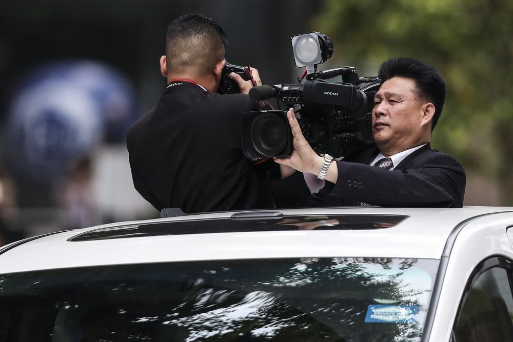 Periodistas norcoreanos filman la caravana de automóviles del líder norcoreano Kim Jong Un, cuando abandonan el hotel St. Regis en camino al Hotel Capella en Singapur, el 12 de junio de 2018, donde tuvo lugar la cumbre entre Kim y el presidente estadounidense Donald Trump. (AP Photo / Yong Teck Lim)