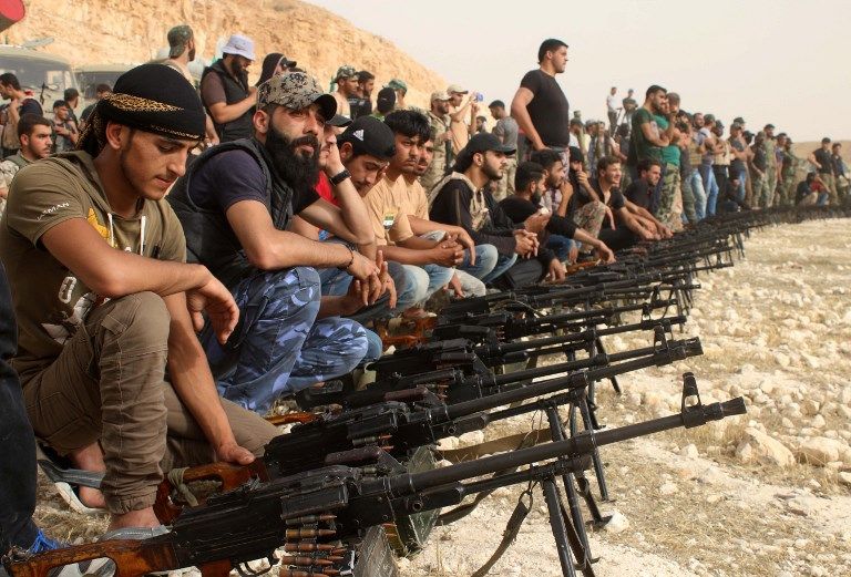 Los rebeldes sirios detrás de ametralladoras desplegadas durante un desfile militar cerca de la ciudad sureña de Daraa el 7 de junio de 2018. (Mohamad ABAZEED / AFP)