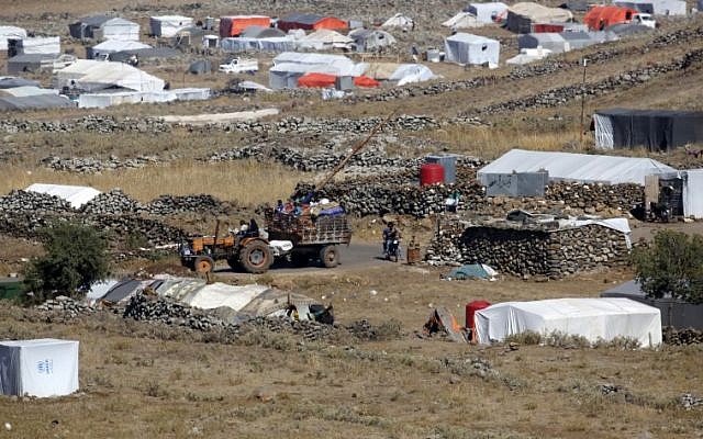 Una fotografía tomada desde los Altos del Golán muestra un remolque conducido por un tractor que transportaba civiles que llegaban a un campamento para sirios desplazados cerca de la aldea siria de Burayqah en la provincia sureña de Quneitra, al otro lado de la frontera con Israel, el 30 de junio de 2018. (AFP Foto / Jalaa Marey)