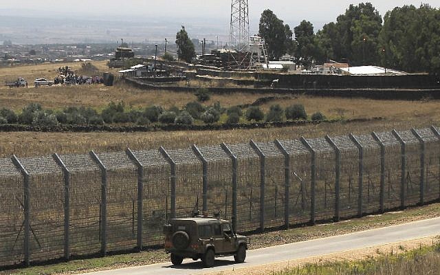 Una imagen tomada el 4 de julio de 2018 desde los Altos del Golán muestra a los sirios desplazados de la provincia de Daraa realizando una protesta (parte superior L) pidiendo protección internacional, en la aldea siria de al-Rafid, cerca de la valla fronteriza con Israel. (AFP / Jalaa Marey)