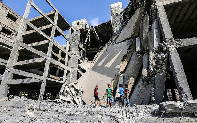 Niños palestinos caminan a través de los restos de un edificio que fue dañado por los ataques aéreos israelíes en la ciudad de Gaza el 15 de julio de 2018. (AFP / MAHMUD HAMS)