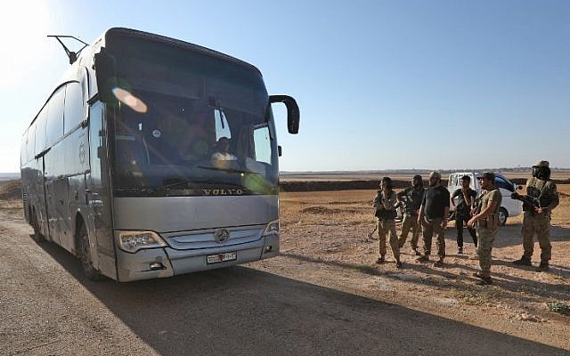 Los miembros del grupo Hayat Tahrir al-Sham, liderados por el ex afiliado de Al Qaeda en Siria, miran cómo los autobuses se preparan para ingresar a las ciudades de Fuaa y Kefraya para evacuar a sus residentes el 18 de julio de 2018 (AFP PHOTO / OMAR HAJ KADOUR)