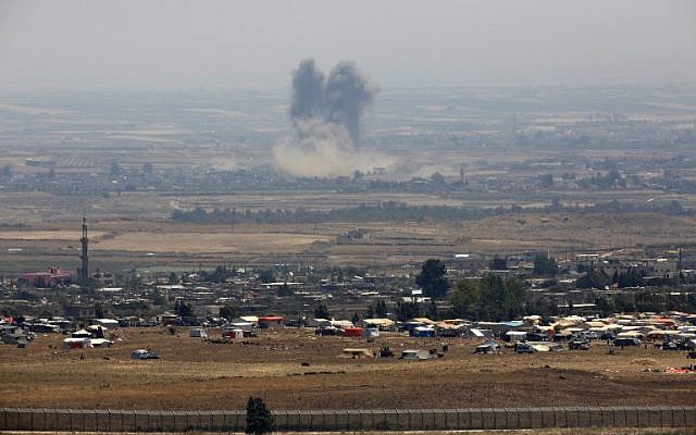 Una imagen tomada el 18 de julio de 2018 de los Altos del Golán israelí muestra humo que se eleva sobre los edificios durante ataques no identificados a través de la cerca fronteriza frente a un campamento para sirios desplazados cerca de la aldea de al-Rafeed en la provincia sureña siria de Daraa. (AFP PHOTO / JALAA MAREY)