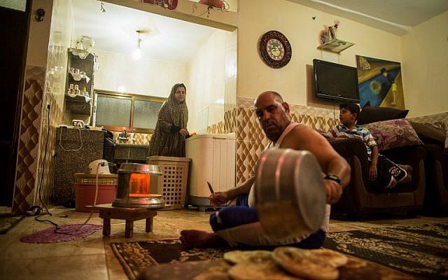 Esta foto tomada el 12 de julio de 2017 muestra a un palestino preparando pan mientras su esposa lava la ropa durante las pocas horas de electricidad que reciben todos los días, en el campo de refugiados de al-Shati en la ciudad de Gaza. (AFP PHOTO / MAHMUD HAMS)