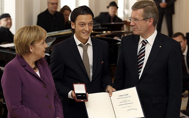 Mesut Ozil, del equipo nacional de fútbol de Alemania, recibe la Hoja de Laurel de Plata de la República Federal del Presidente alemán Christian Wulff, derecha, y la Canciller alemana Angela Merkel, izquierda, en Berlín, Alemania, el martes 5 de octubre de 2010. (AP Photo / Michael Sohn)