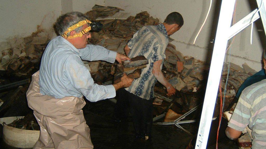 Los voluntarios intentan recuperar el material de archivo judío iraquí del sótano inundado de Mukhabarat, cuartel general de inteligencia de Saddam Hussein, 2003. (Harold Rhode, cortesía de los Archivos Nacionales de los EE. UU.)