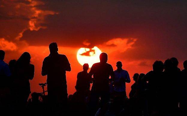 La gente se reúne mientras esperan que se ponga el sol y la aparición de la “luna de sangre” en Berlín el 27 de julio de 2018. (AFP / Tobias Schwarz)