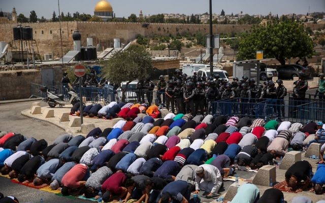 Los musulmanes rezan mientras los policías israelíes vigilan durante las oraciones del viernes en el barrio de Jerusalén Este de Ras el Amud, en las afueras de la Ciudad Vieja, el 28 de julio de 2017 (Hadas Parush / Flash90)